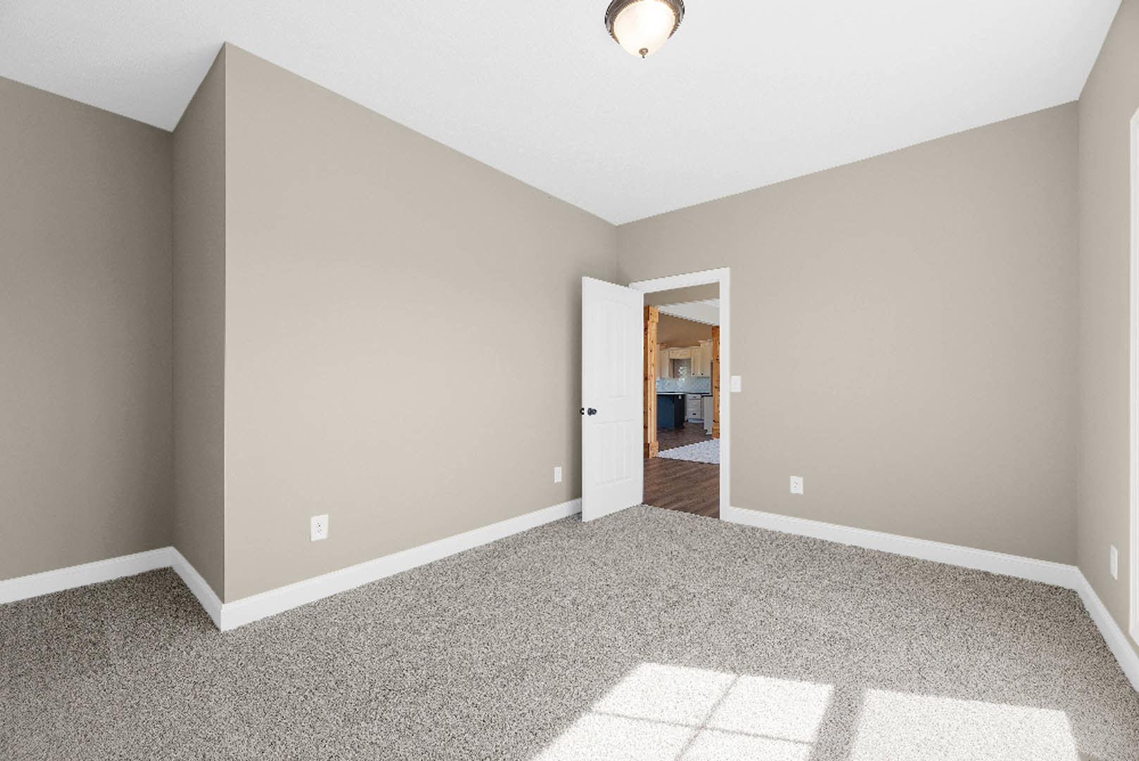 White door with blue knob opening to kitchen with wooden frame, carpeted floor in foreground, plaster walls, and laminate flooring visible in kitchen.