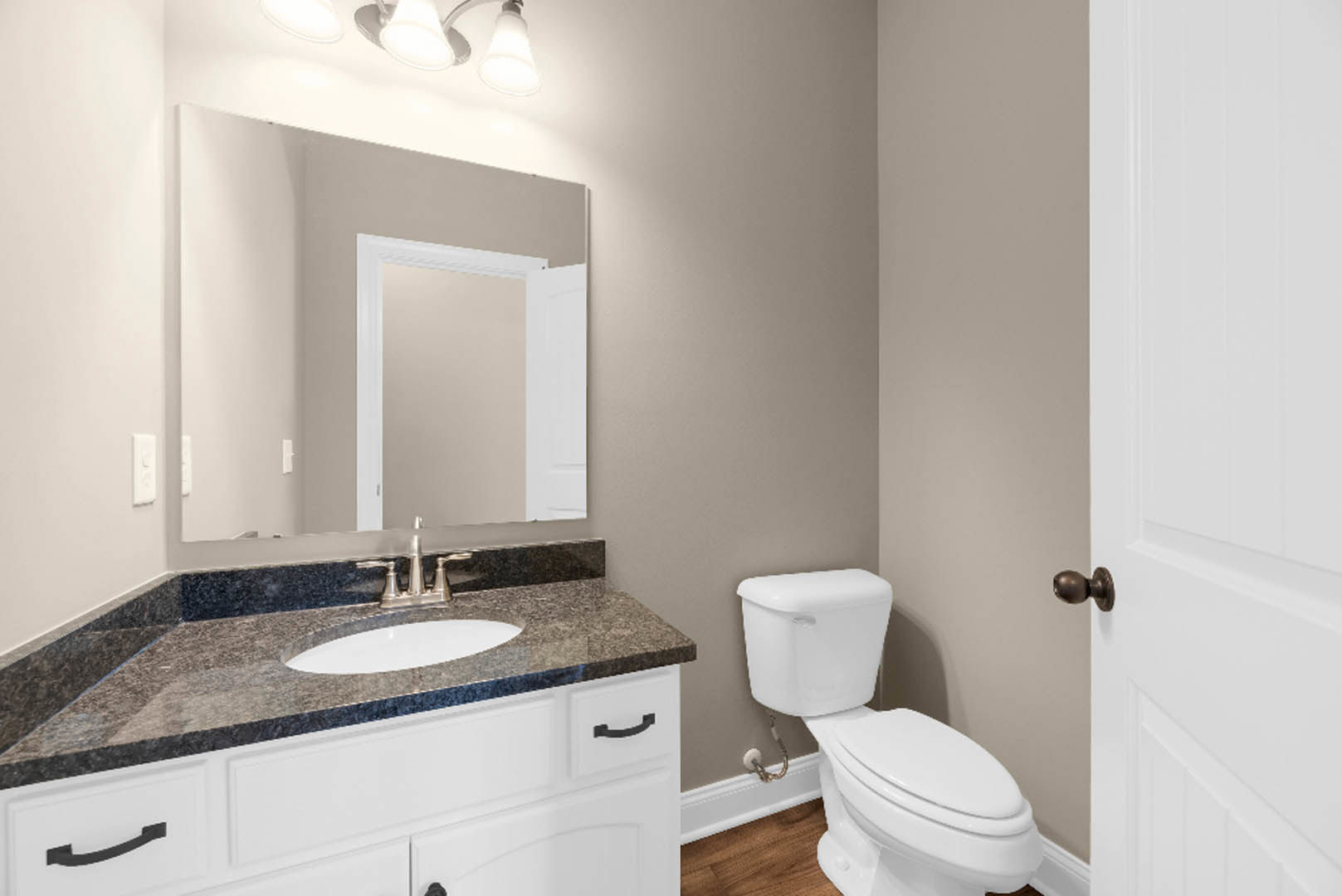 Modern bathroom featuring white tile walls, a wall-mounted sink with chrome faucet, a white toilet, rectangular mirror above the sink, and black trim accents