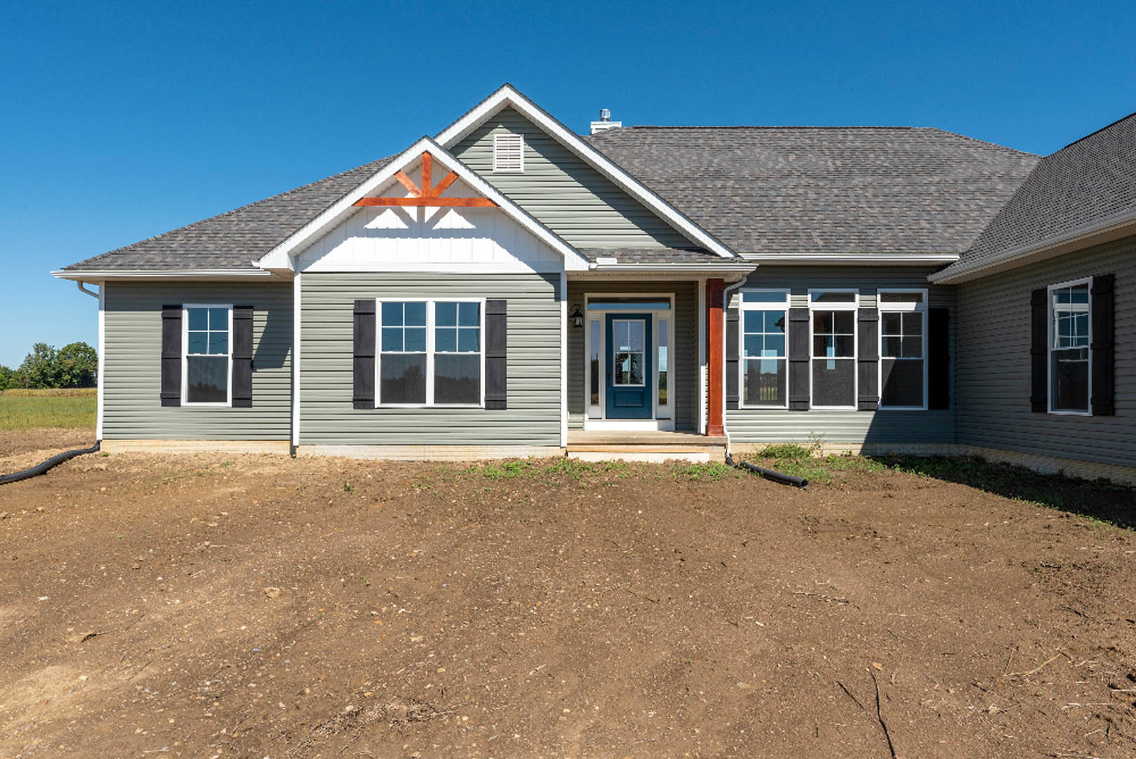Two-story house with light siding, blue front door with white trim, dirt yard, white vent above window, gabled roof, and multiple windows