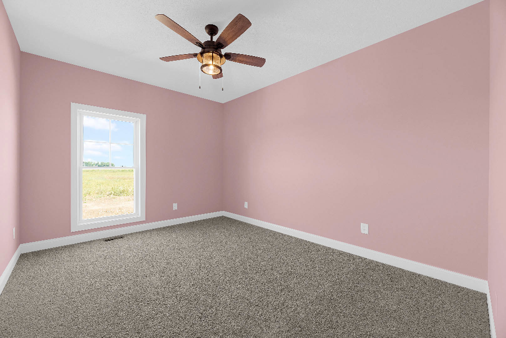 Carpeted bedroom with pink walls, white ceiling fan with light, large window overlooking grassy field and blue sky