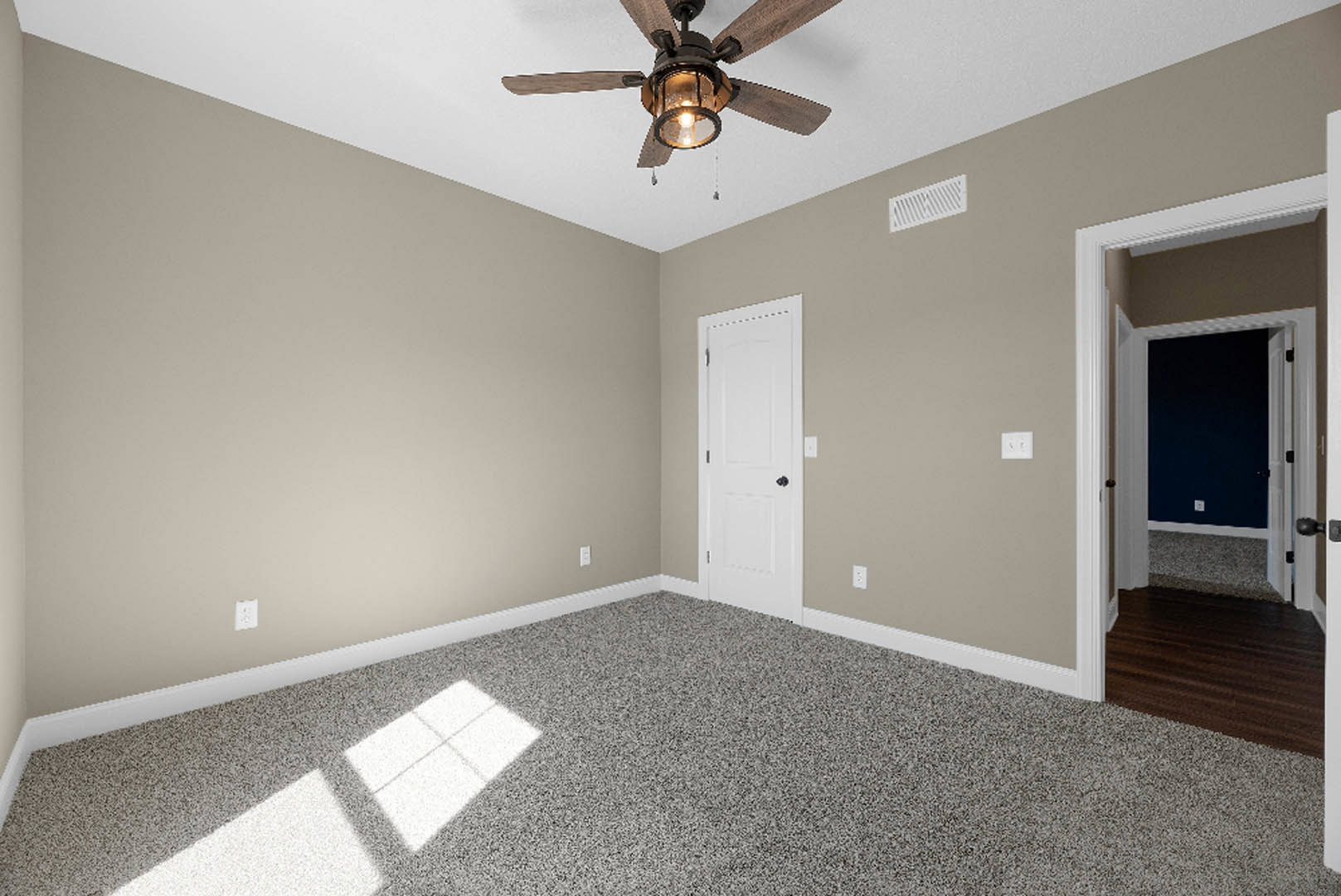 Dark blue wall with white trim, dark wood floor, white door with black knob, ceiling fan with light bulb, close-up window, plaster ceiling