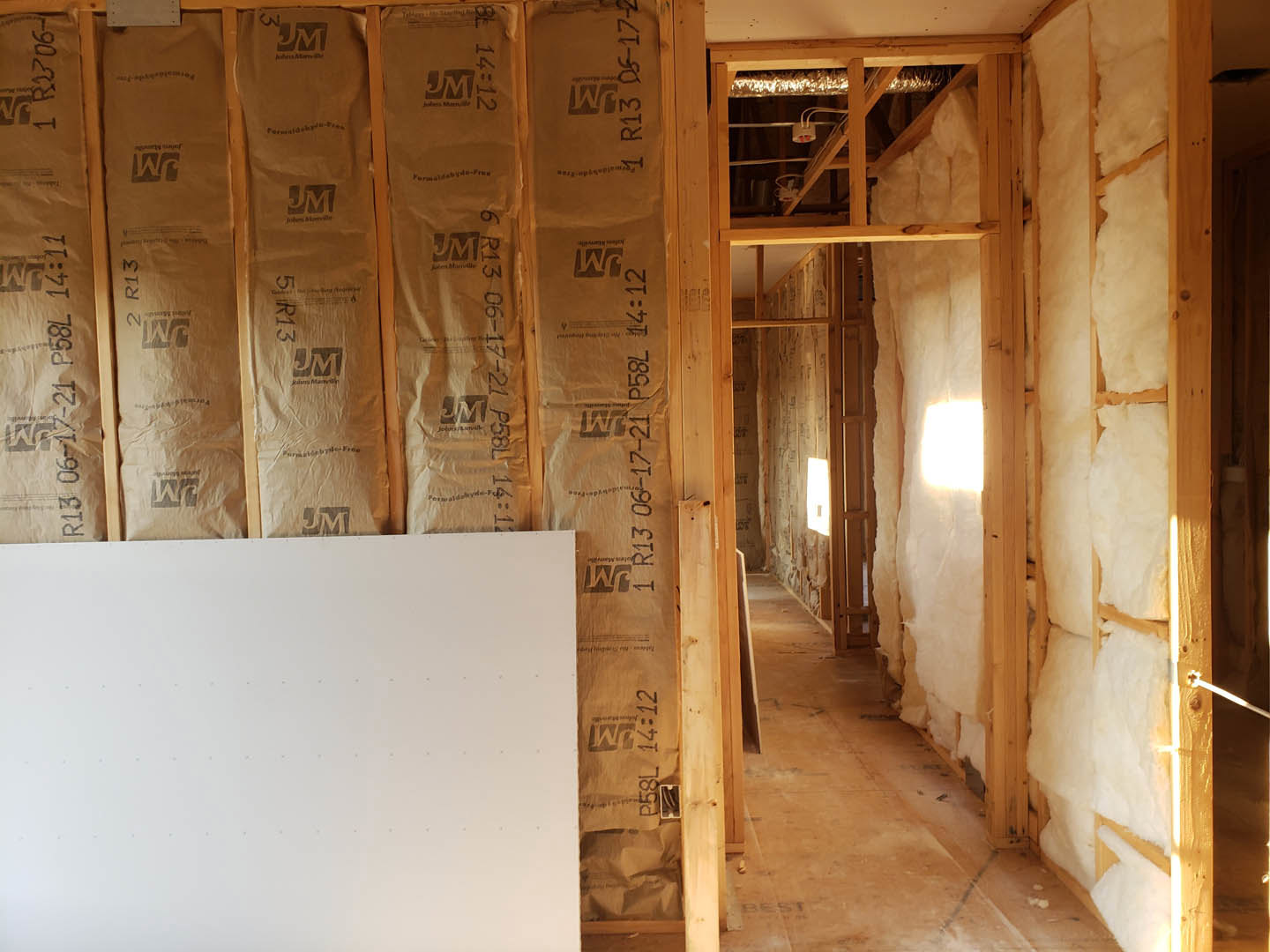 Living room with exposed wood ceiling beams, plaster walls, and a feature wall covered in brown paper bags with black text and logos.