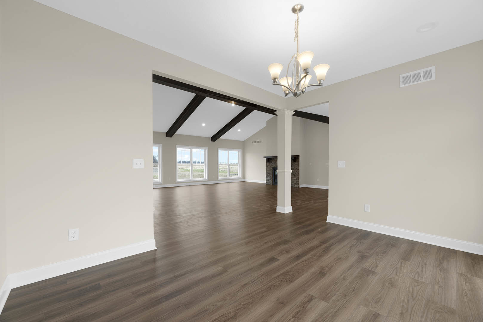 Spacious room featuring wood plank flooring and matching wood ceiling, plaster walls, large window overlooking a field, ceiling vent, and decorative chandelier.
