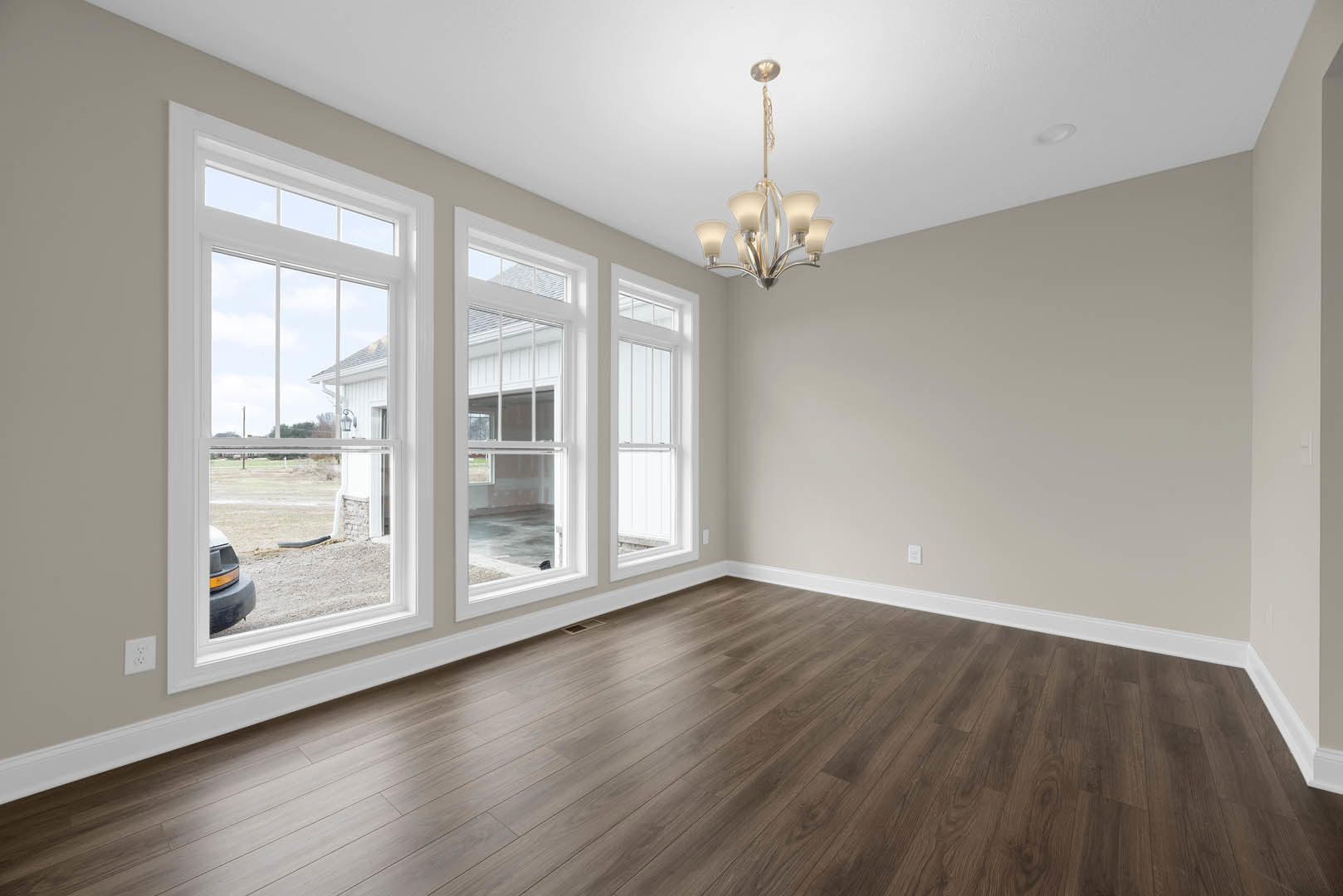 Chandelier with white shade hanging in a room featuring hardwood floors, white-trimmed windows, plaster walls, and decorative molding