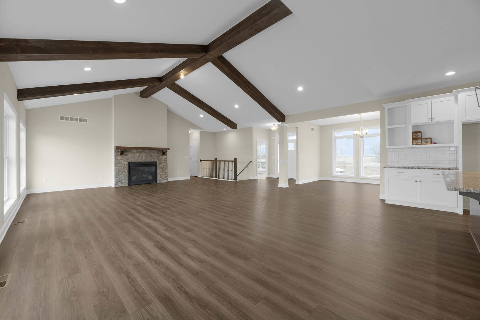 Spacious room with hardwood floors, exposed wooden ceiling beams, plaster walls, and a glass-door fireplace with wood burning inside