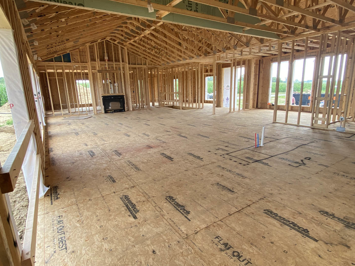 Living room with wood flooring, stone fireplace, exposed ceiling beams, and neutral walls