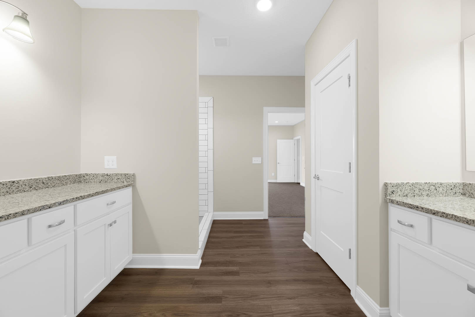 Bathroom featuring white cabinetry, marble countertops, wood flooring with white trim, silver door handles, and a white electrical outlet on the wall.