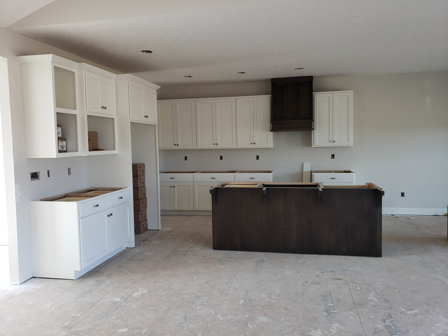 White shaker cabinets, dark wood island with waterfall countertop, stainless steel appliances, light tile flooring, recessed lighting, and subway tile backsplash
