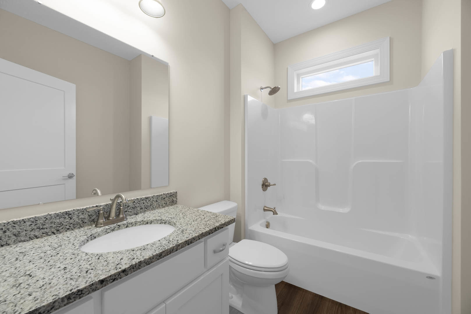 Modern bathroom featuring a white bathtub, toilet, and rectangular sink with chrome faucet, light gray tile walls, a window showing blue sky, and a white door with black handle