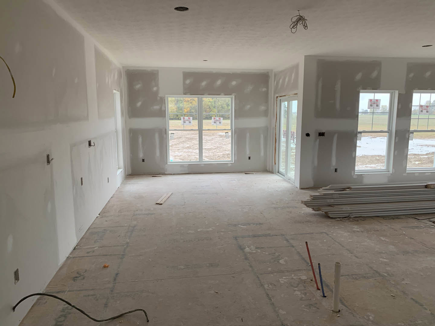 White plaster walls, large window with daylight, light wood flooring, minimal interior finishes