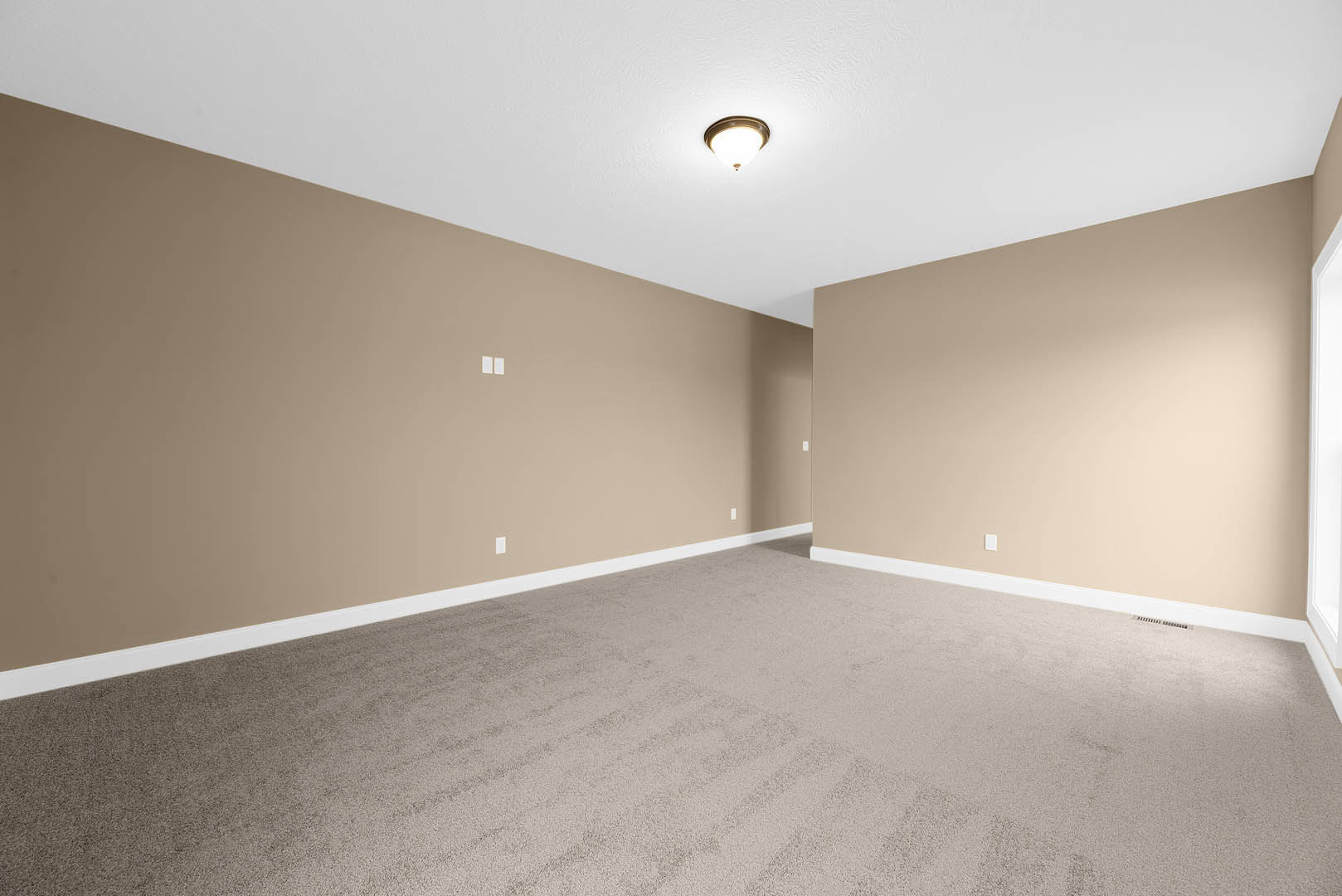 Carpeted room with beige walls, white rectangular window, and ceiling-mounted light fixture