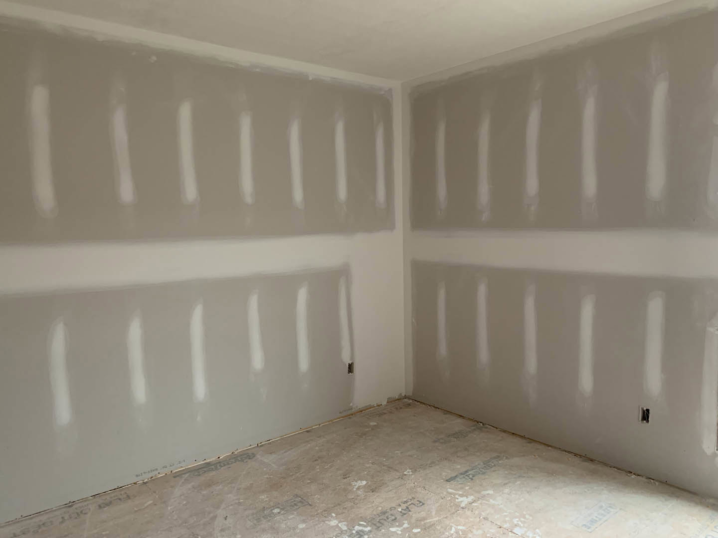 White-painted walls, concrete floor, white ceiling with recessed light, wall with visible holes and white lines, unfinished interior remodel.