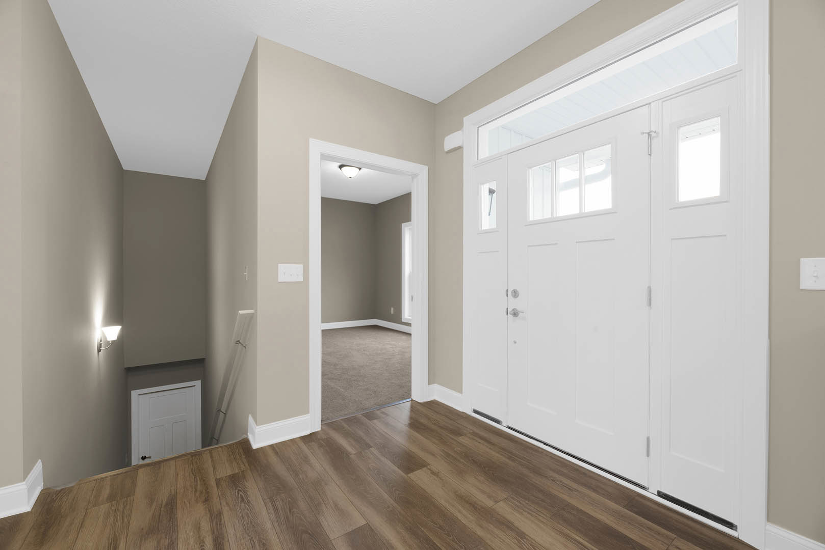 Hallway with white paneled doors, light wood flooring, and neutral walls