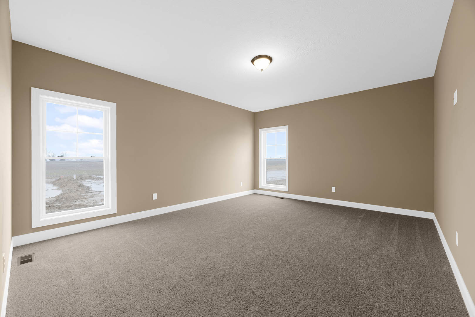 Carpeted bedroom with white plaster walls, large window overlooking ocean beach, ceiling light fixture, crown molding