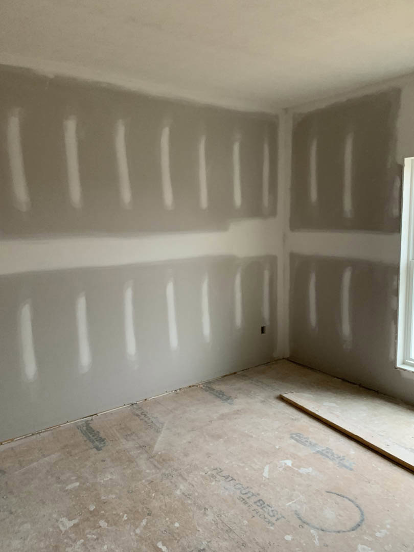 Bright room with white painted walls, light wood flooring, and smooth plaster ceiling