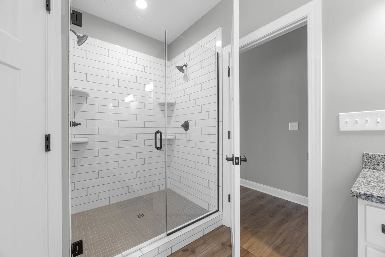 Bathroom featuring a frameless glass shower enclosure, tiled walls and floor, modern shower head, white countertop with integrated sink, black square drain cover, and white light