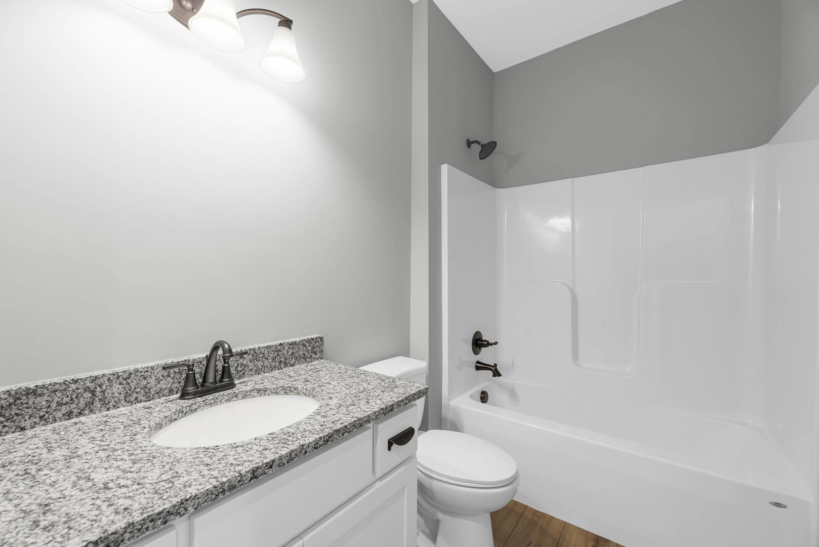 Bathroom with marble countertop, undermount sink, chrome faucet, freestanding white bathtub, and white toilet against tiled walls
