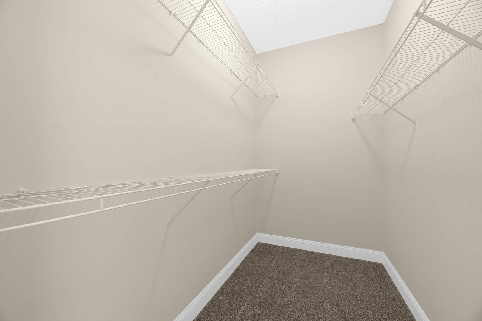 White built-in shelves mounted on a plaster wall above light gray carpet flooring in a residential room with a white ceiling.