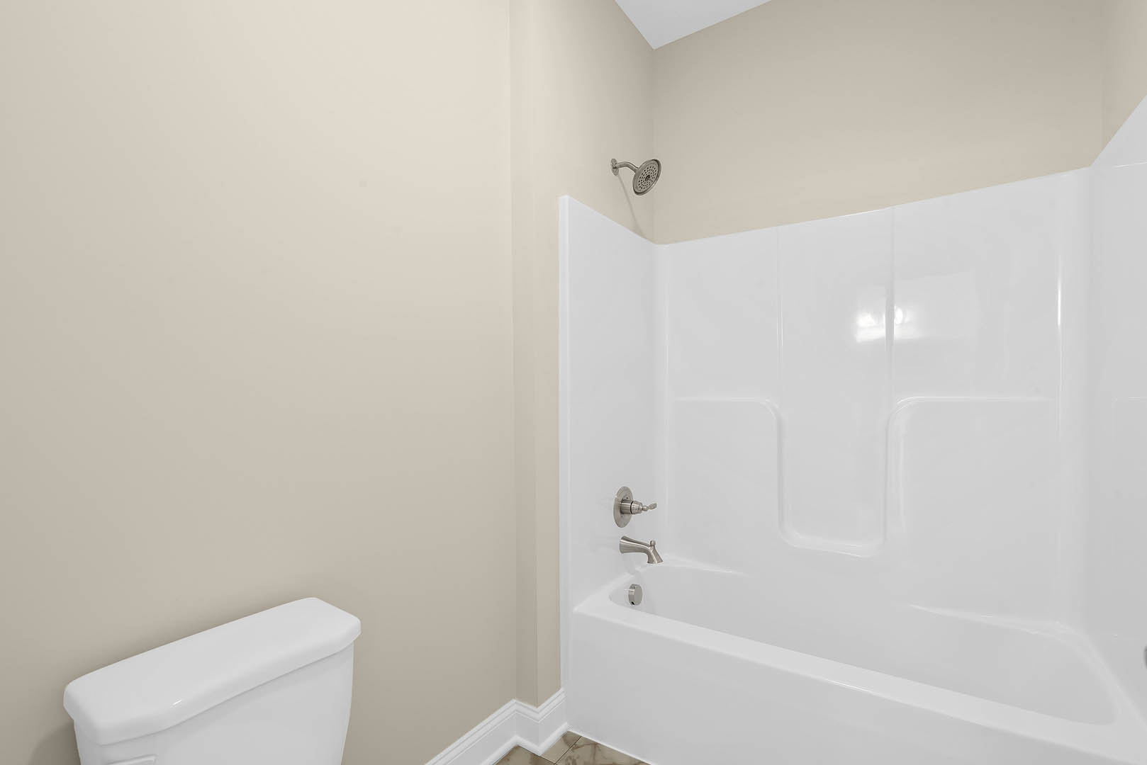 Bathroom with white tile walls, freestanding bathtub, modern toilet, chrome faucet, handheld shower head, and brushed metal door knob