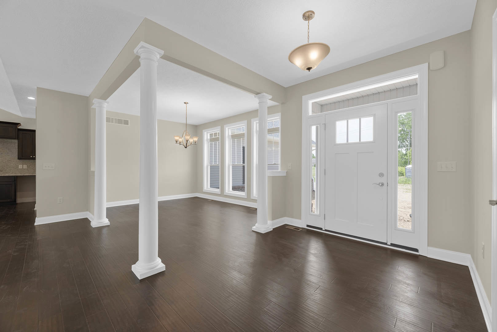 Wood flooring room with white columns, glass-paneled white door, ceiling light fixture, and plaster walls