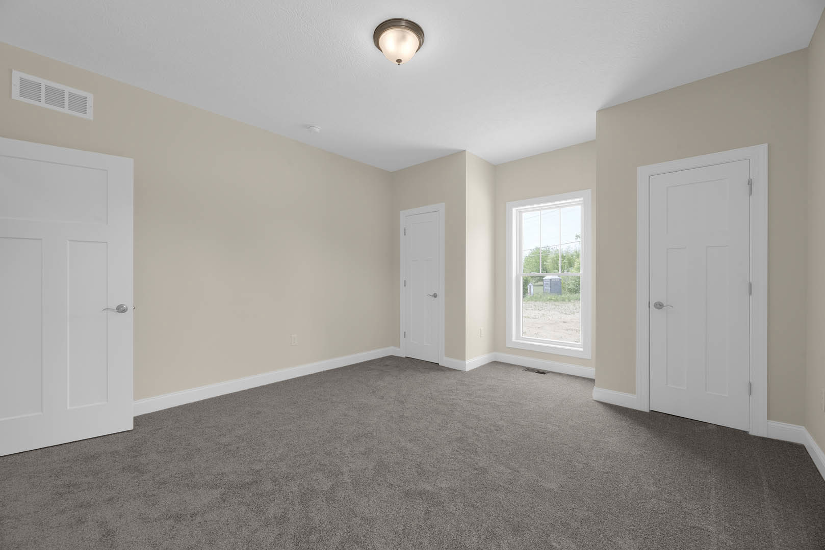 Carpeted room with white paneled doors, silver handles, white walls, ceiling light fixture, window overlooking grassy field, simple baseboard molding