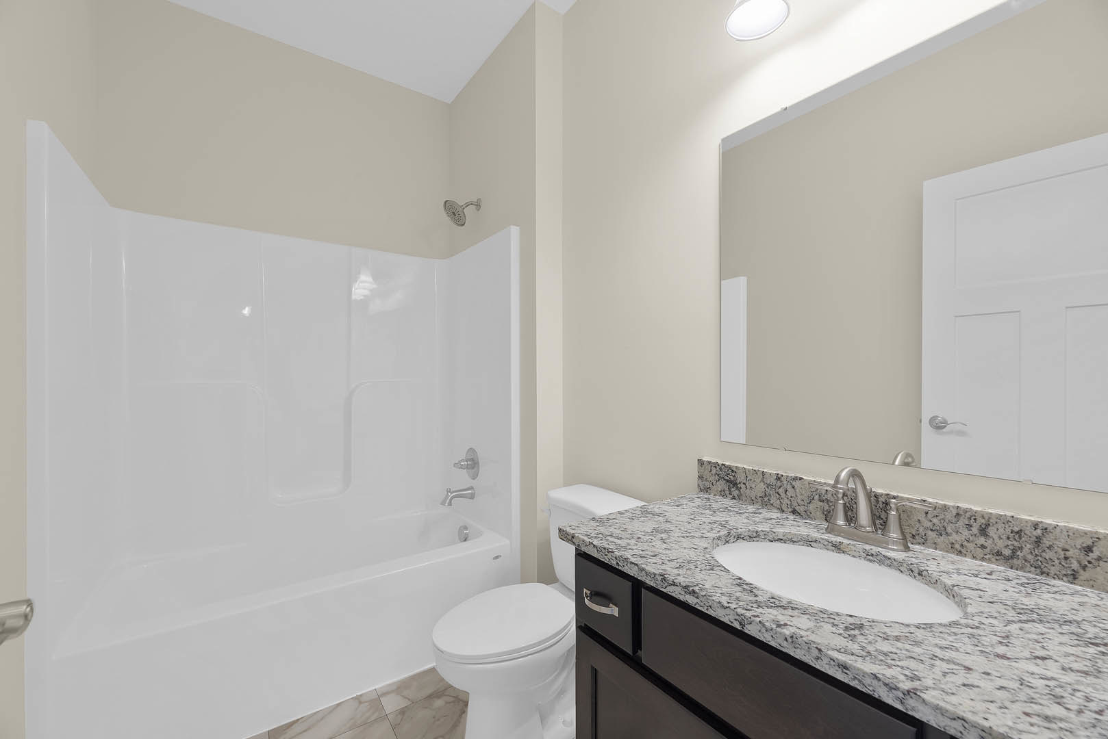 Bathroom with marble countertop, freestanding bathtub, tiled walls, chrome fixtures, and white cabinetry