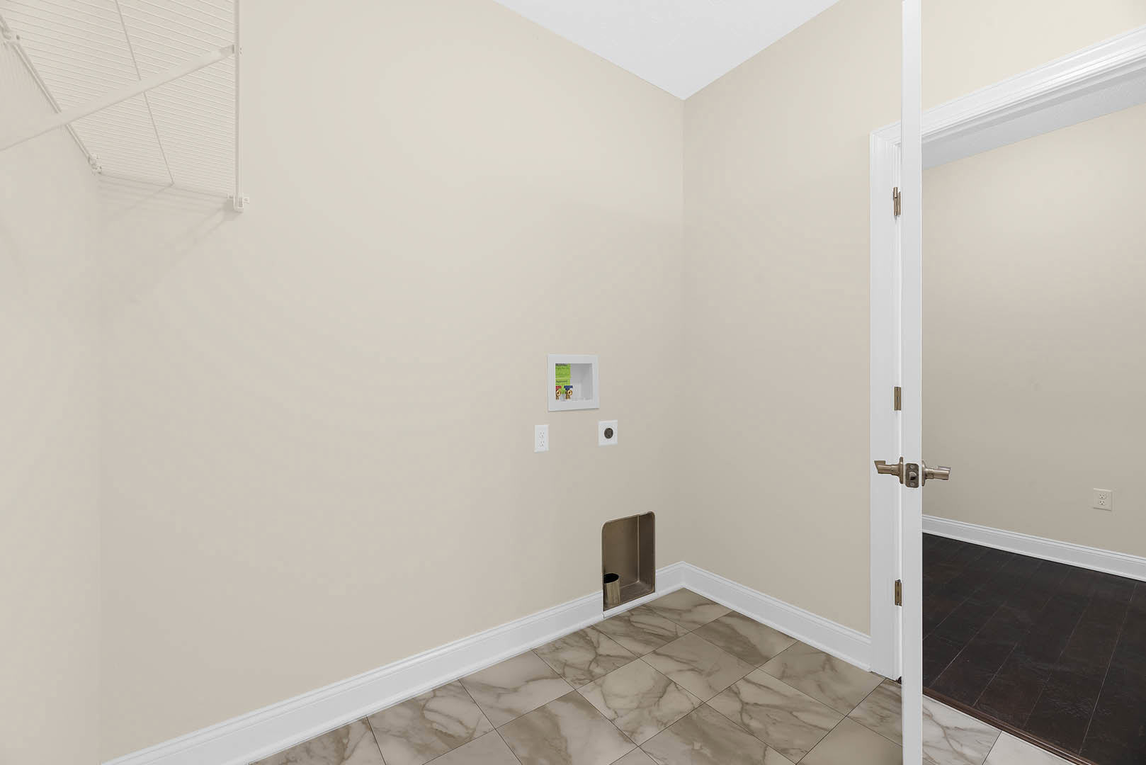Dark brown tile flooring, white ceiling with linear detailing, open door, white-framed square panel with exposed brass pipes, metal fixture in corner