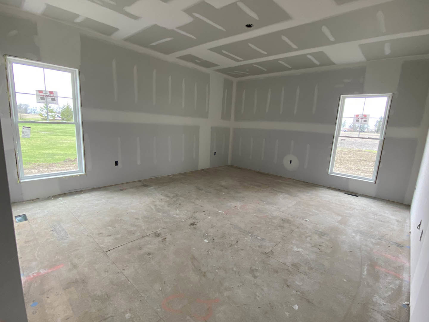 Spacious room featuring large windows, smooth concrete flooring, white plaster walls, and ceiling with daylight streaming in.