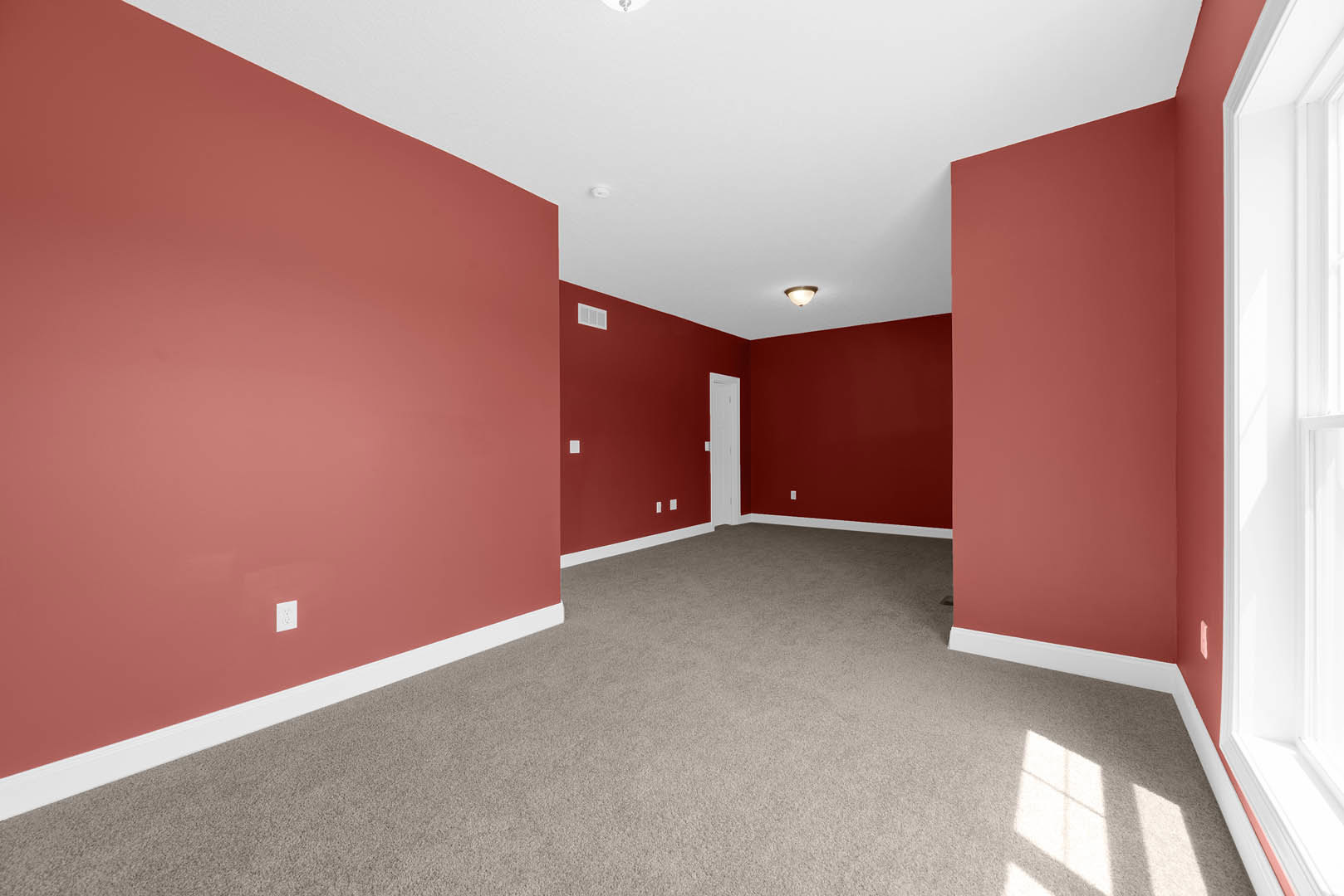 Room with deep red walls, white ceiling, white trim, and plush red carpet flooring