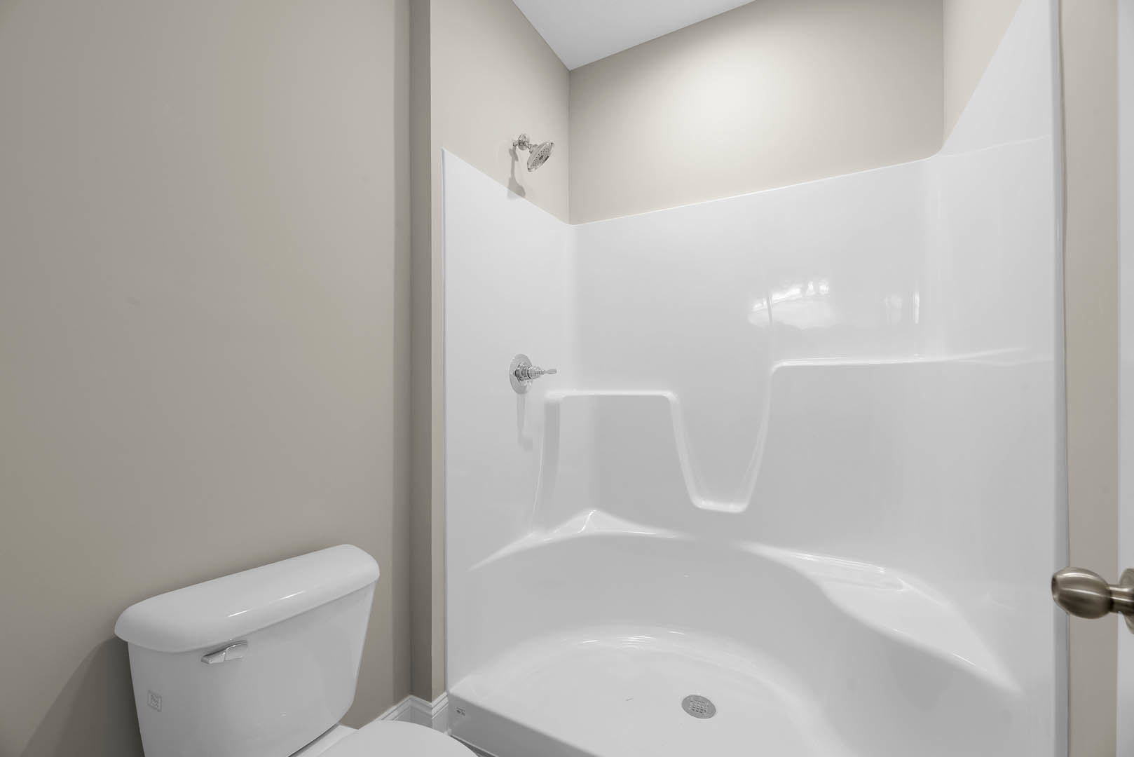Modern bathroom with white tile walls, glass shower enclosure, white toilet, chrome fixtures, and built-in shelving