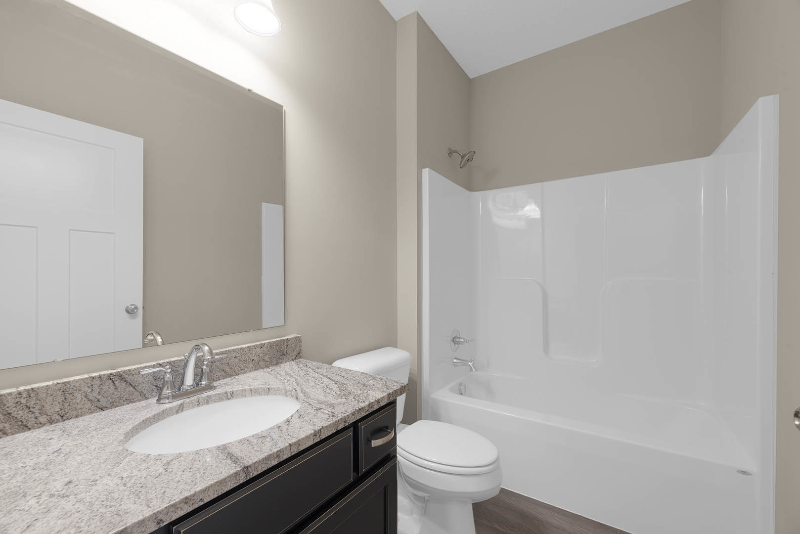 Bathroom with white freestanding tub, modern sink vanity, chrome faucet, and tiled walls; toilet positioned beside bathtub.