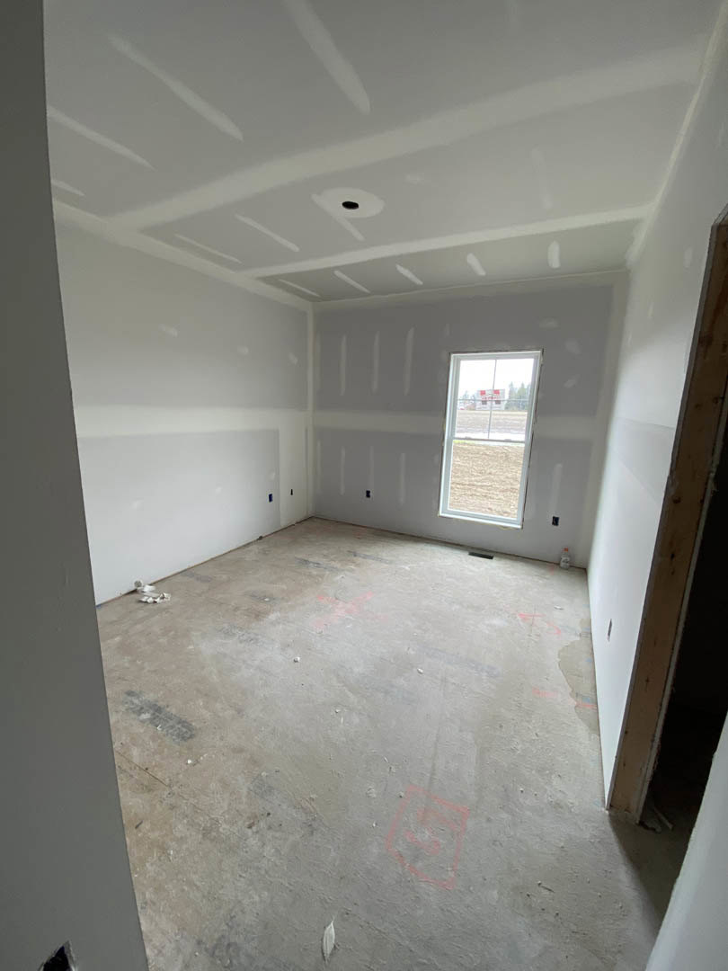 Concrete floor with smooth finish, white plaster walls, large window framed in wood, white ceiling with linear painted accents, exterior sign visible through glass