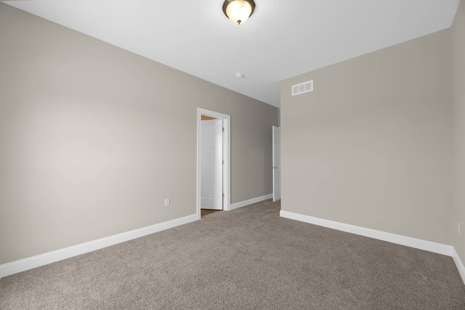 Carpeted room with white baseboards, white paneled door, ceiling vent, and flush mount ceiling light fixture.