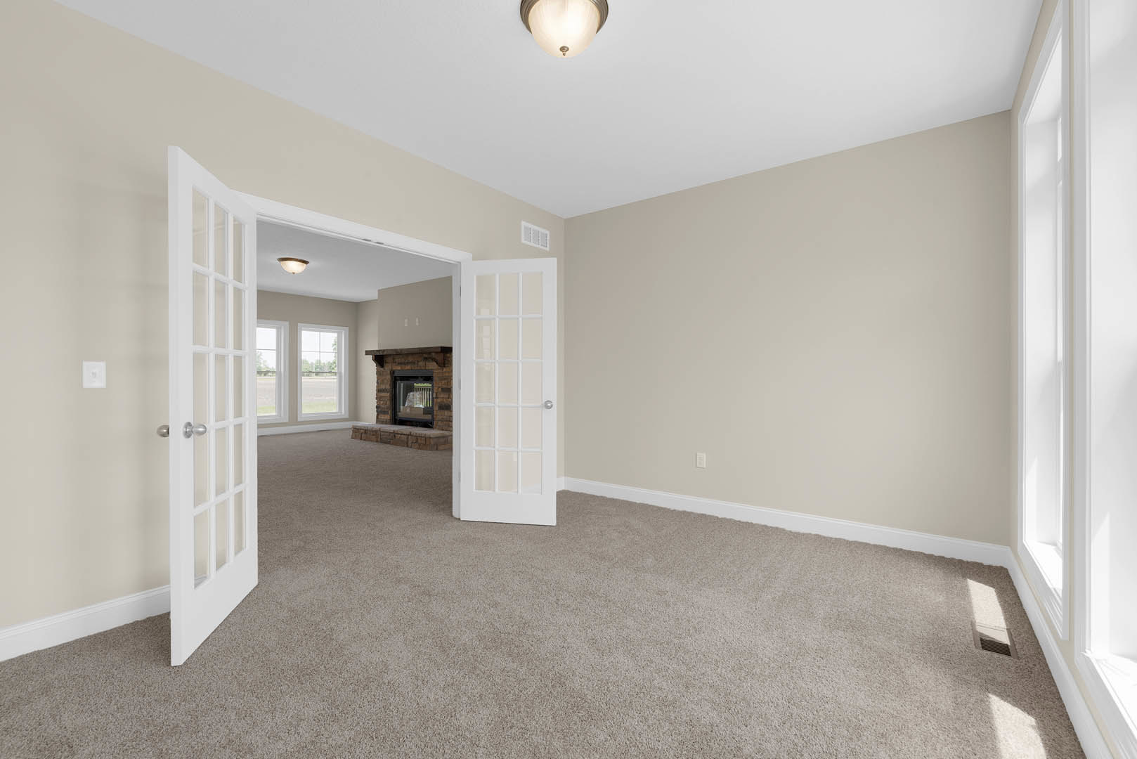 Carpeted living room with white paneled door featuring glass panes, plaster walls, fireplace with glass window, crown molding, and laminate flooring
