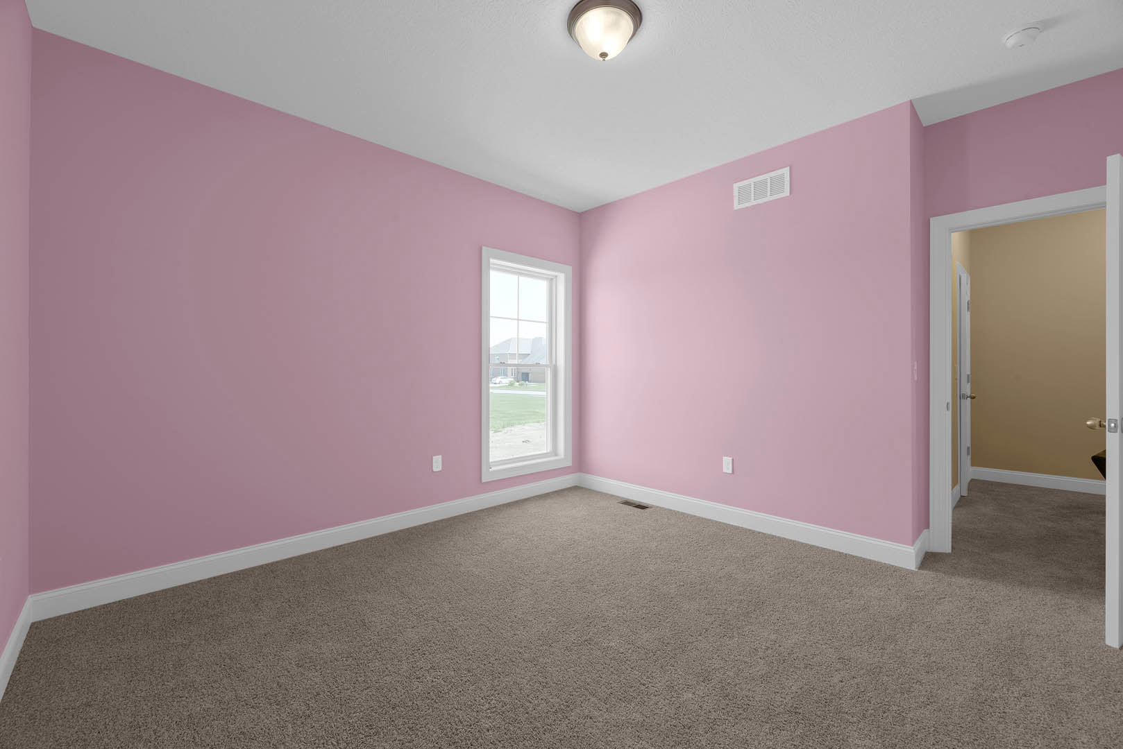 Pink plaster walls, white trim window with exterior house view, open door leading to adjacent room, beige carpet flooring, ceiling light fixture, wall vent