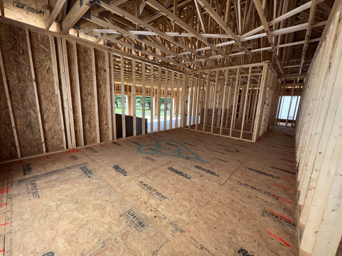 Open room with exposed wood ceiling beams, unfinished wood floor, and framed window with vertical bars