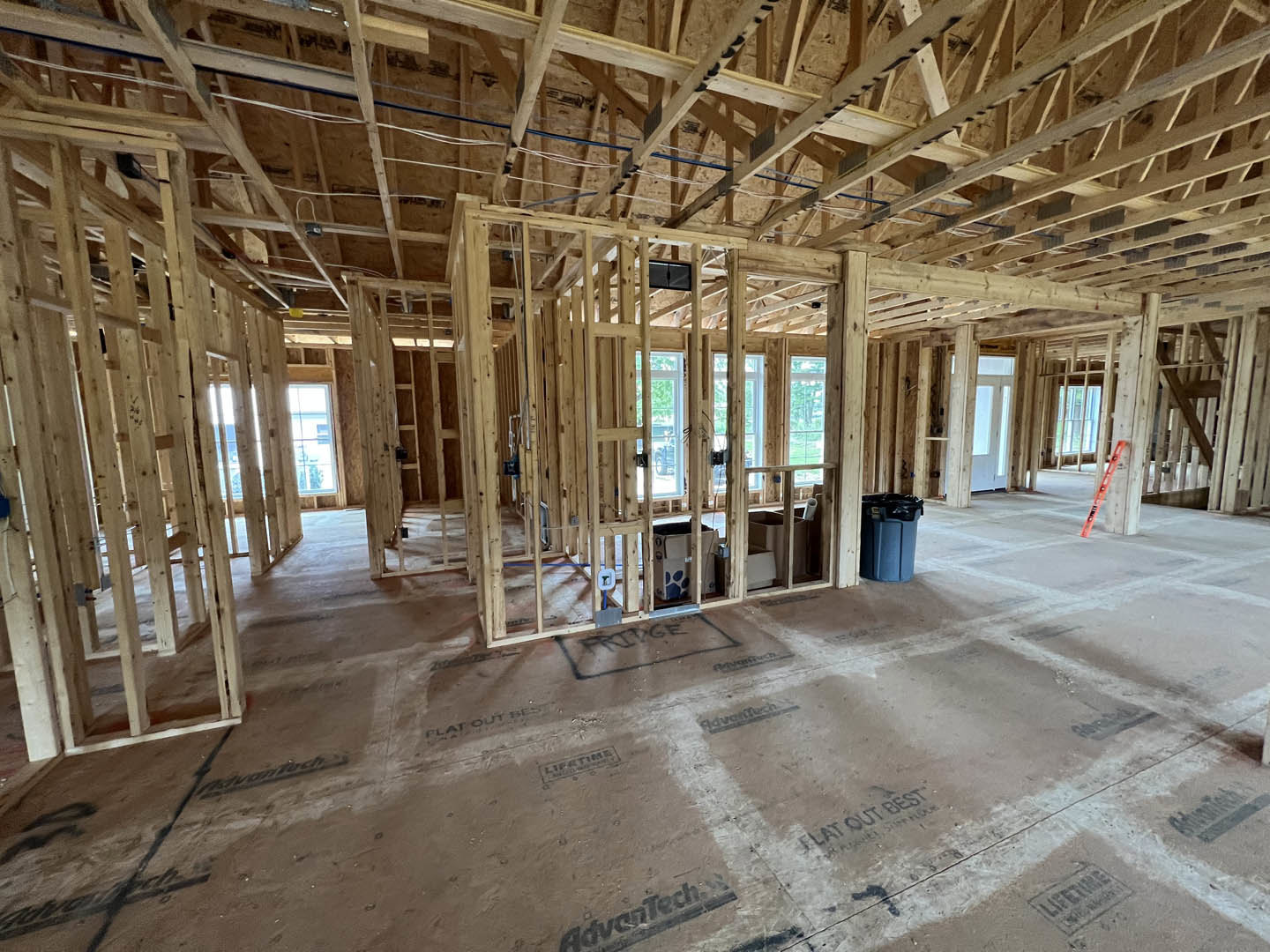 Wood-framed room under construction with exposed beams, unfinished walls, and a metal ladder leaning against the wall