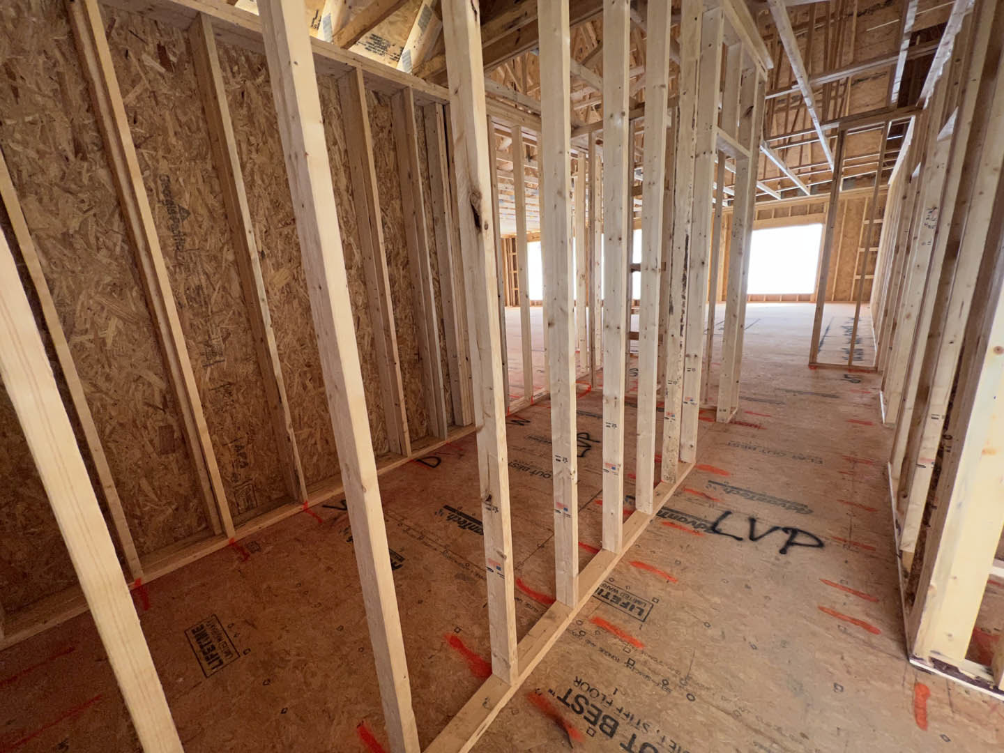 Exposed wood framing and beams inside unfinished room with visible insulation and construction materials