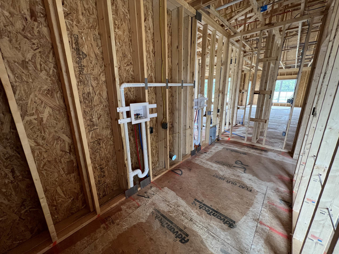 Wood-framed room with exposed white pipe running along unfinished wall