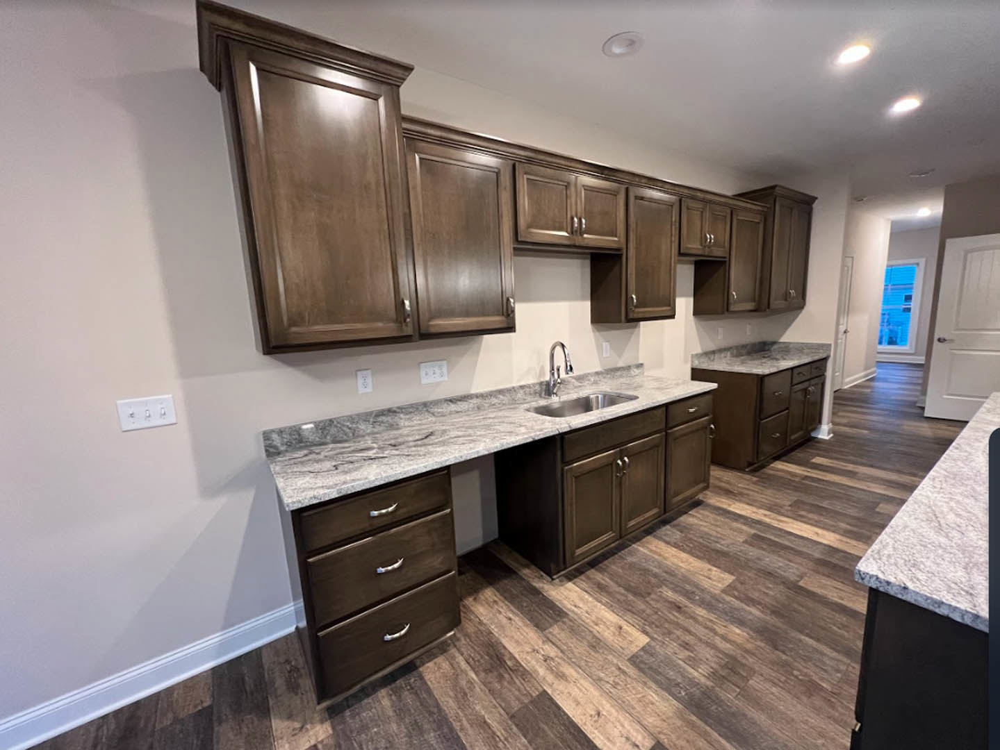 Kitchen with dark wood cabinetry, granite countertops, stainless steel sink, tile backsplash, and modern fixtures
