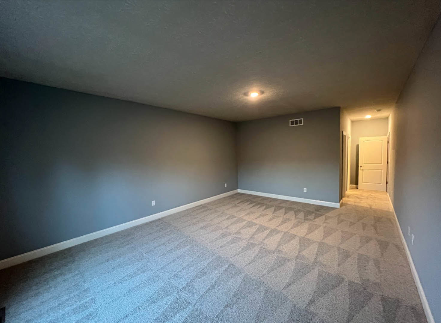 Carpeted room with blue wall, white door featuring silver handle, white ceiling with recessed light fixture