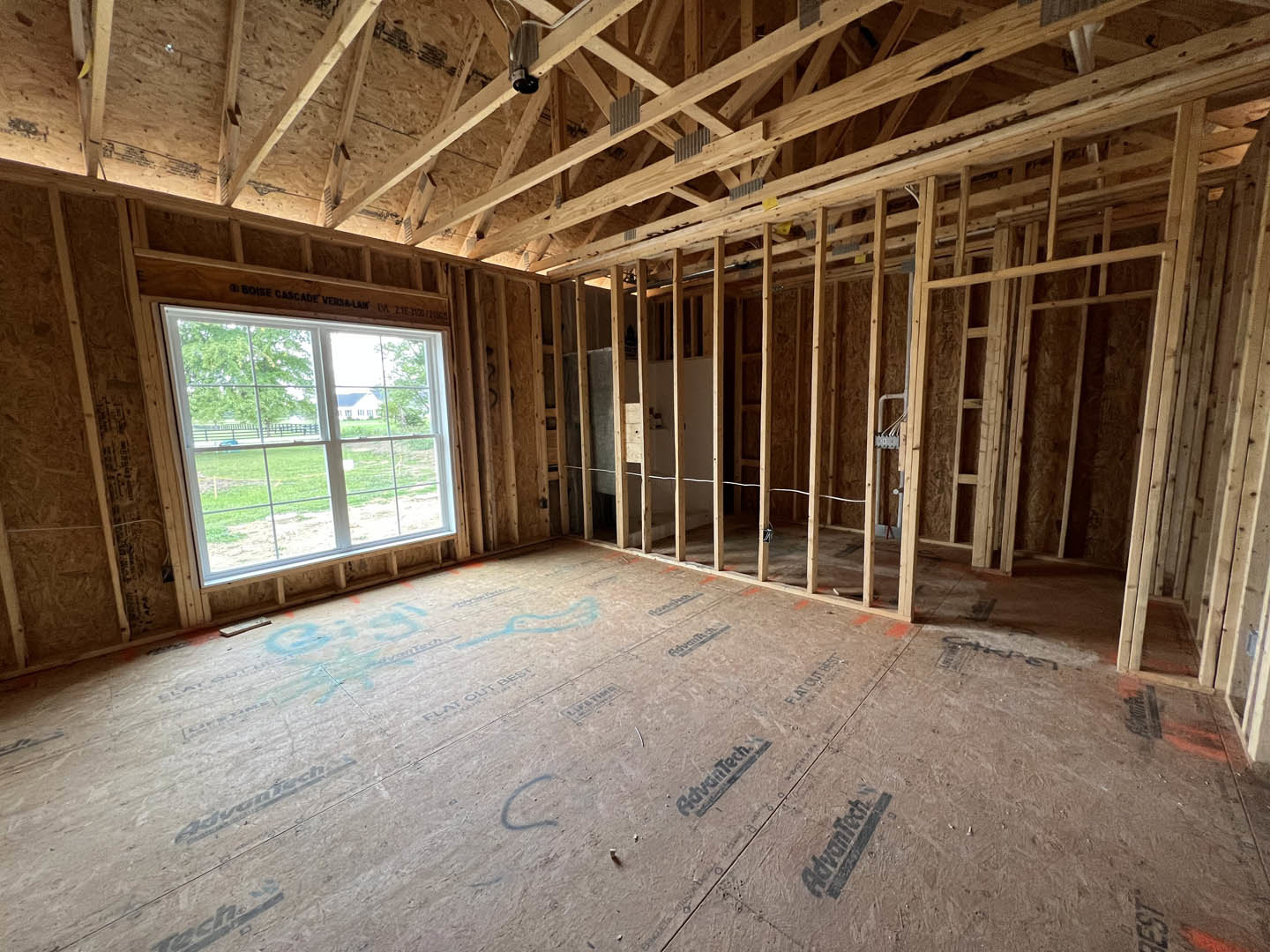 Living room with exposed wood ceiling beams, large window, light-colored walls, and hardwood flooring