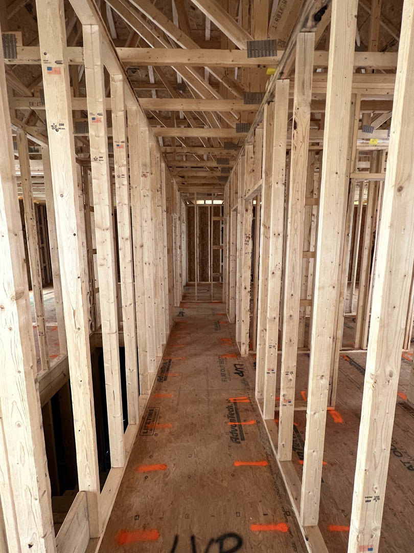 Exposed wood framing and beams inside a house under construction, unfinished lumber and planks forming walls and ceiling structure