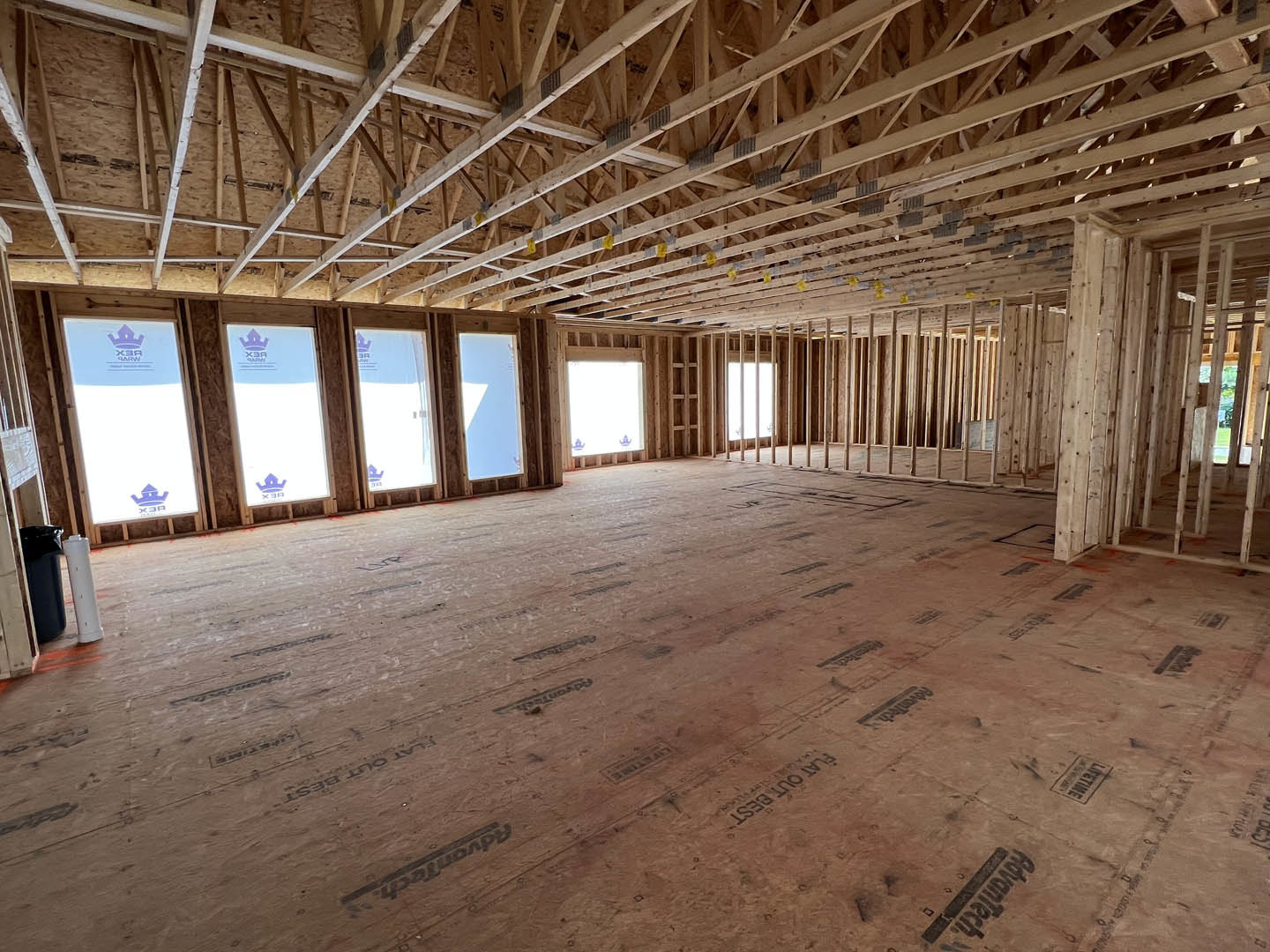 Living room with exposed wood ceiling beams, large windows, and light-colored flooring