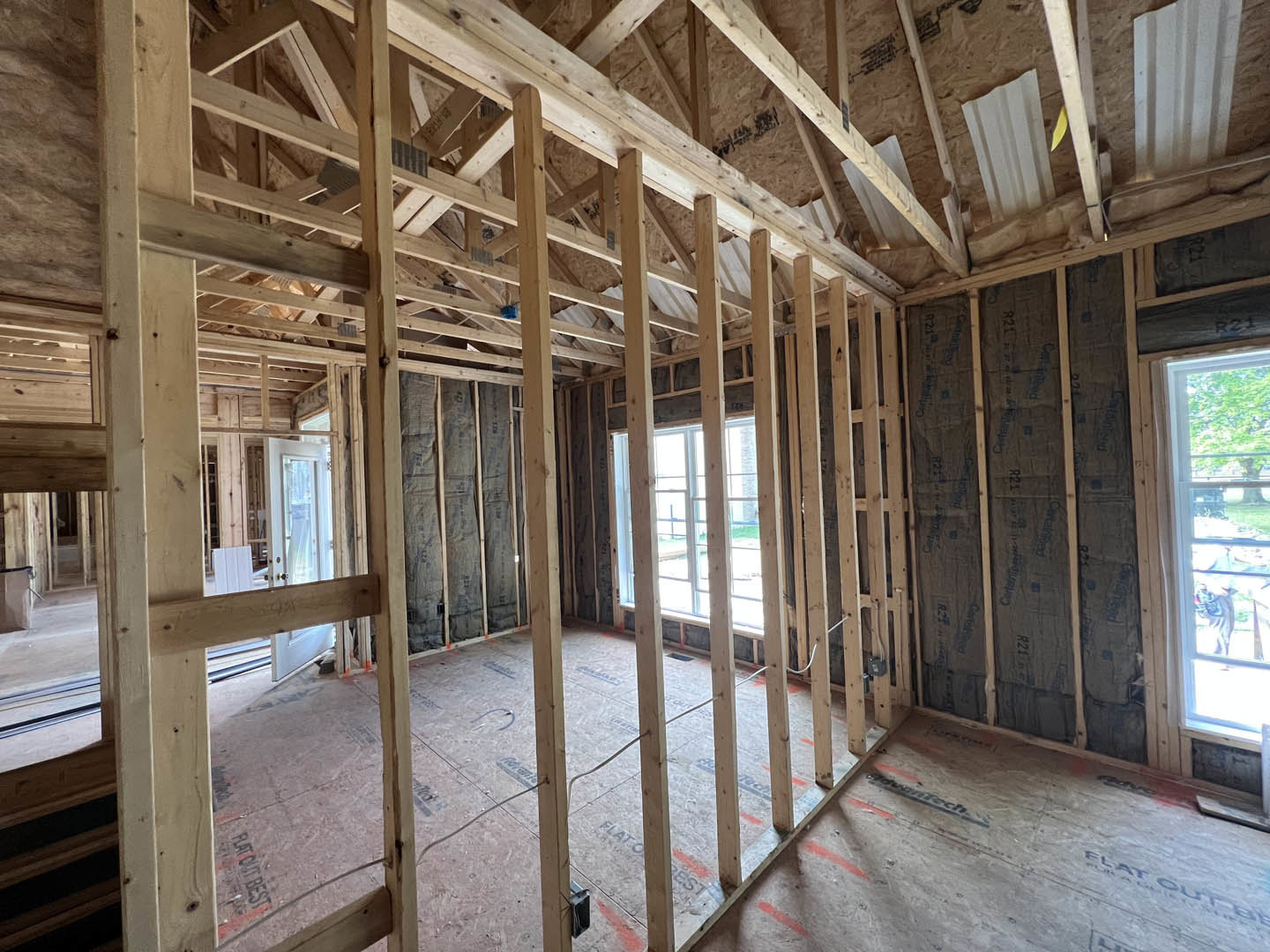 Living room with exposed wood ceiling beams, large window overlooking grassy yard and trees, white square decor with wooden frame, blurred dog in foreground