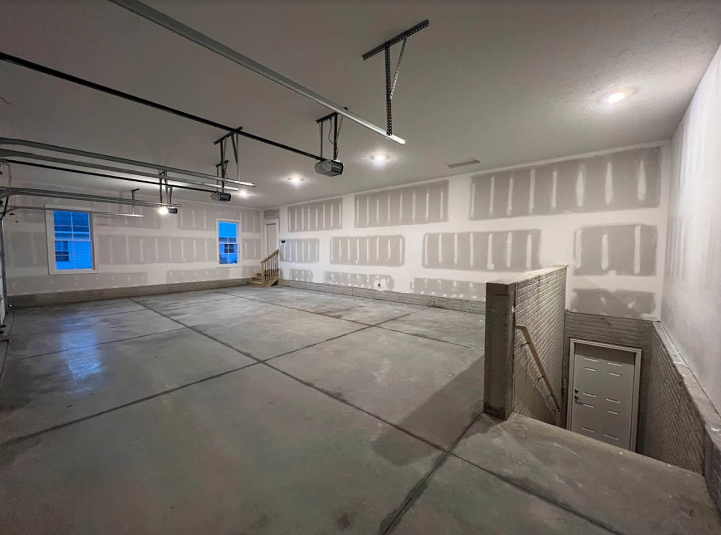 Modern interior room featuring a painted accent wall, white door with black handle, brick wall with ladder, close-up views of a window and staircase, concrete floor, and composite