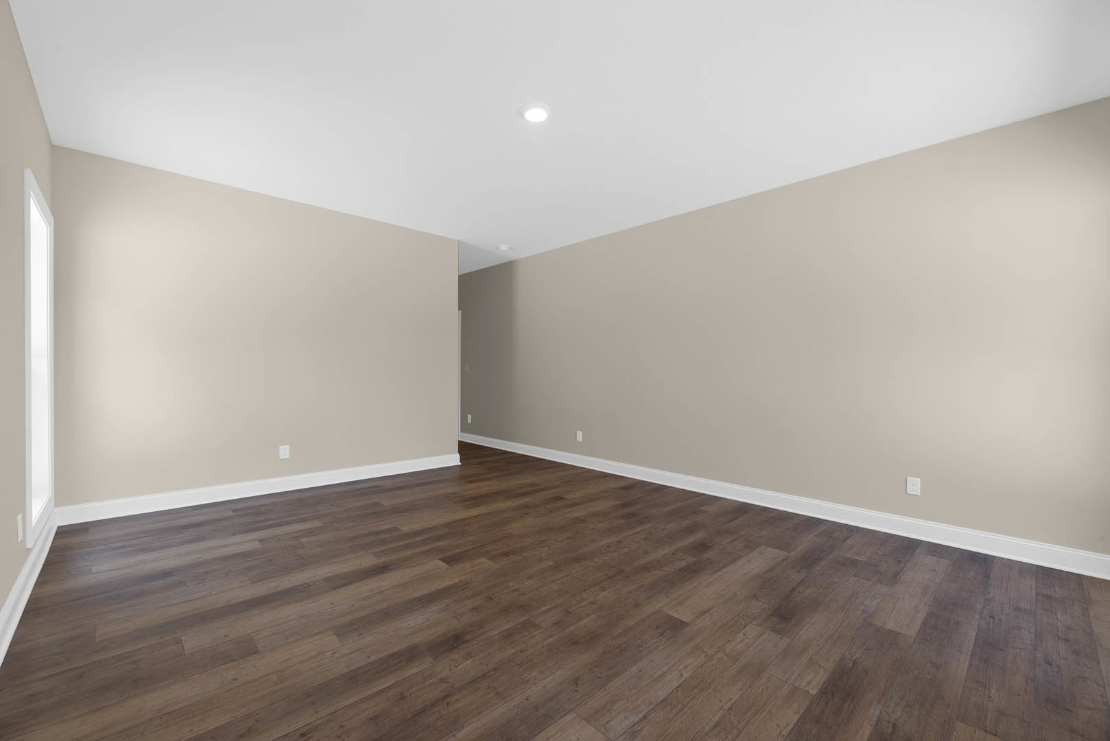 Wood flooring with rectangular planks, white plaster walls, ceiling light fixture, and a rectangular window letting in natural light