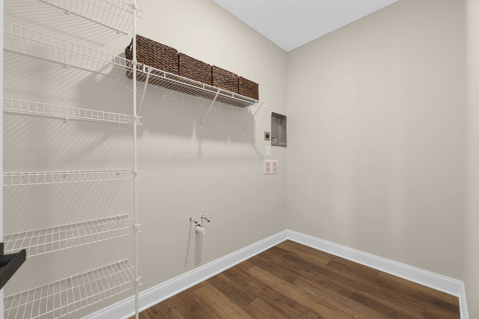 White plaster walls with a built-in shelf holding woven baskets, light wood flooring with white baseboards, and minimal decor in a modern residential room.