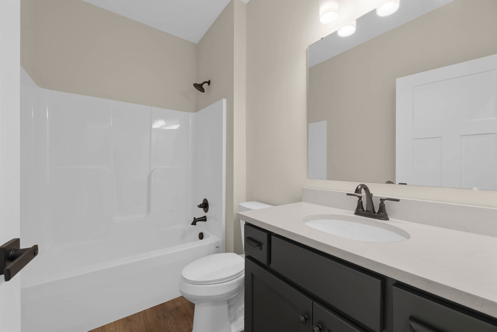 Modern bathroom featuring a freestanding bathtub, white ceramic sink with chrome faucet, tiled walls, white toilet, paneled door, and wall-mounted shower head