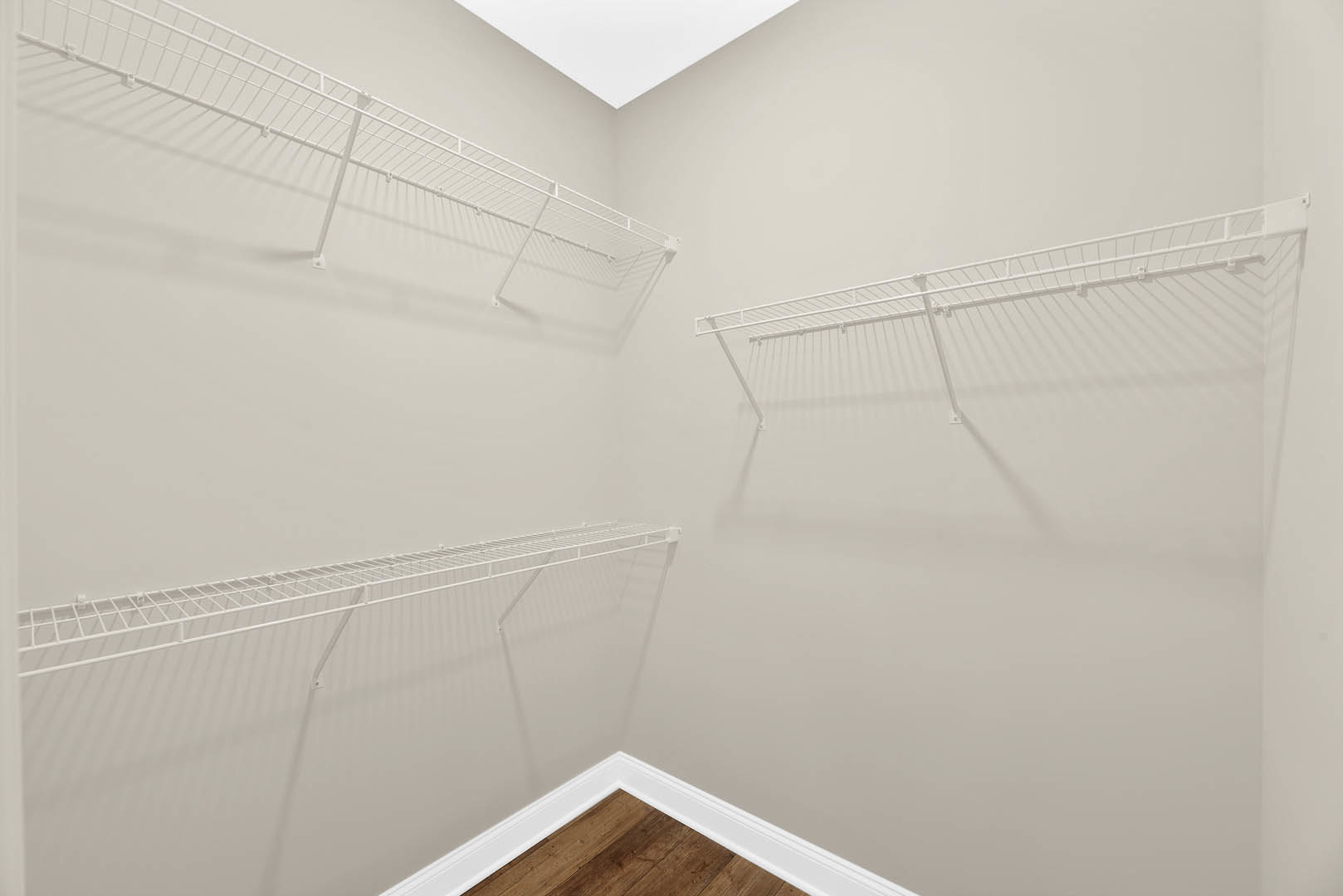 Corner of a room with white plaster walls, built-in white shelves, white ceiling, and decorative white molding.